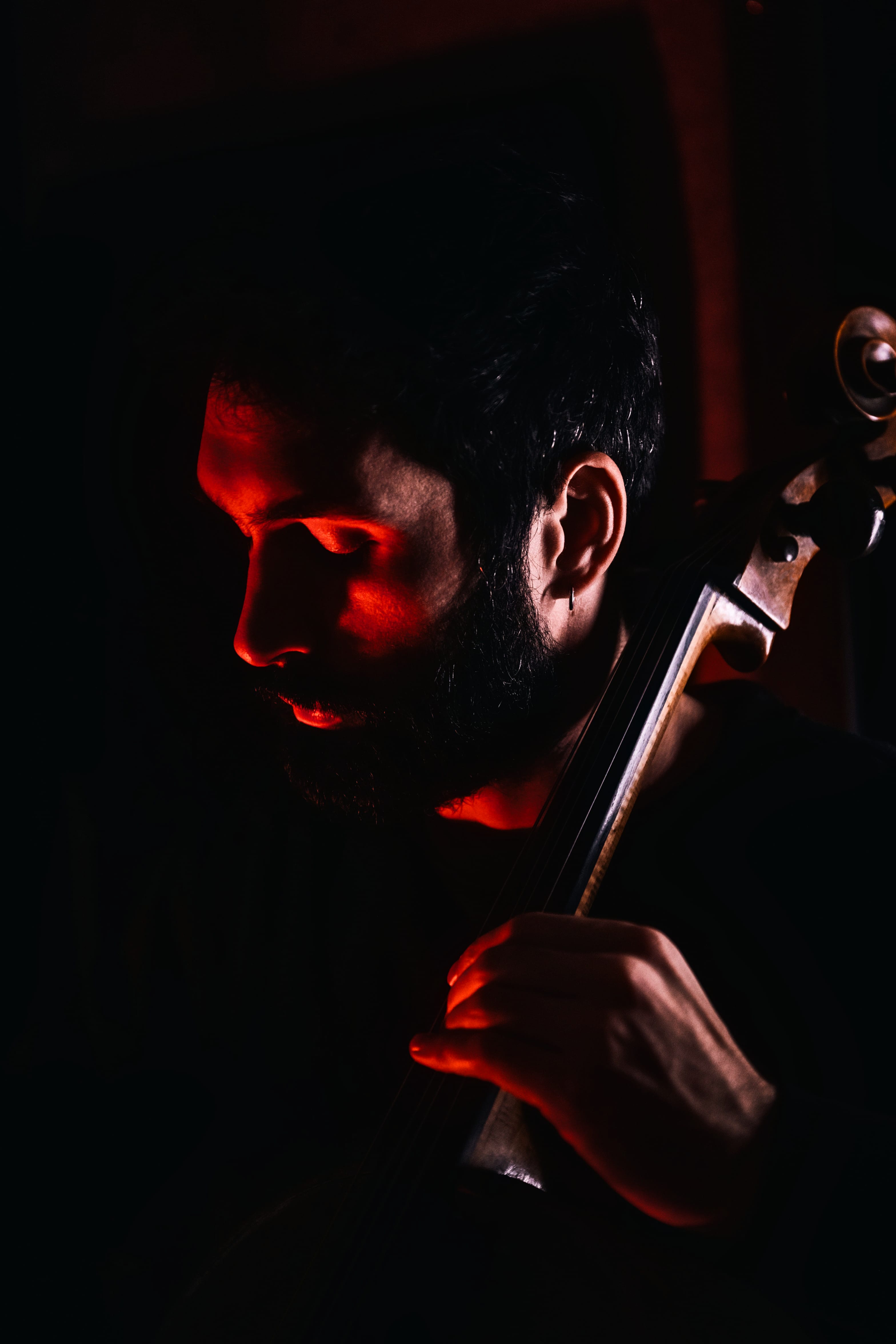 Antonio Cortesi is playing the cello in a dark and red atmosphere